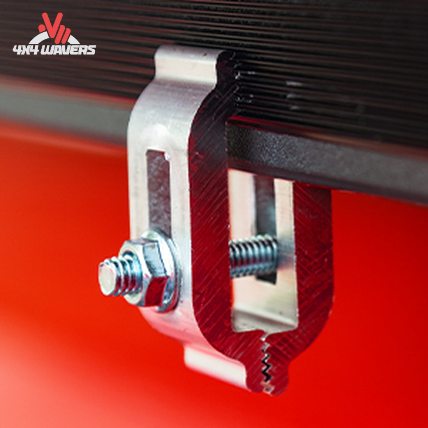 Close-up of a metallic clamp assembly with a hex bolt and threaded rod, attached to a black ribbed panel against a bright red background.