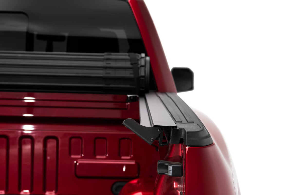 BAK Revolver X4s hard roll-up tonneau cover with side rail seal system on Jeep Gladiator 5ft bed, matte black aluminum slats.