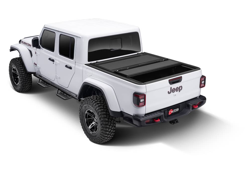 BAKFlip MX4 hard folding tonneau cover in matte aluminum on Jeep Gladiator 5ft bed, folded with tailgate lock system visible.