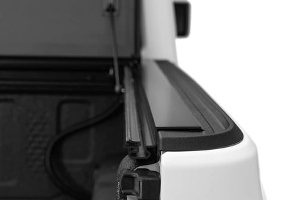 Close-up of BAKFlip MX4 hard folding tonneau cover tailgate locking system on Jeep Gladiator with matte aluminum finish.