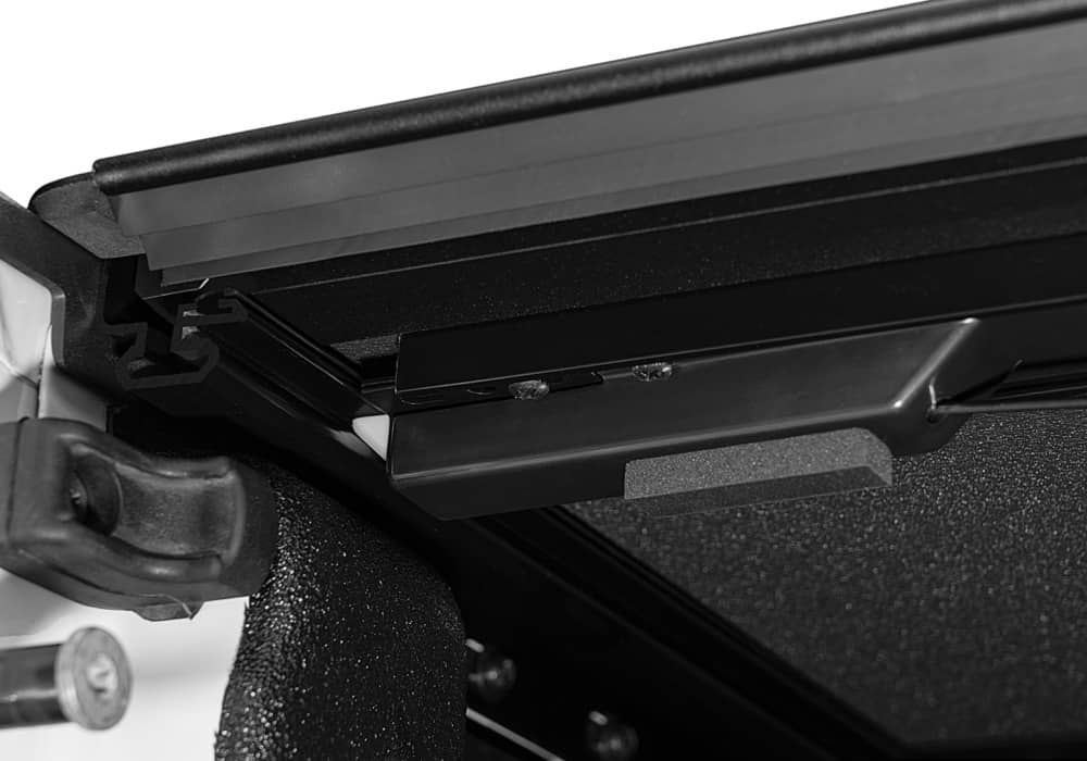 Close-up of the BAKFlip MX4 hard folding tonneau cover tailgate locking system on a Jeep Gladiator with matte aluminum finish.