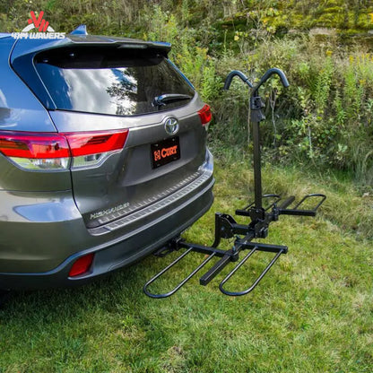 Portabicicletas CURT tipo bandeja para 2 bicicletas instalado en un SUV, compatible con receptores de 1-1/4" y 2", diseñado para transportar bicicletas con seguridad.