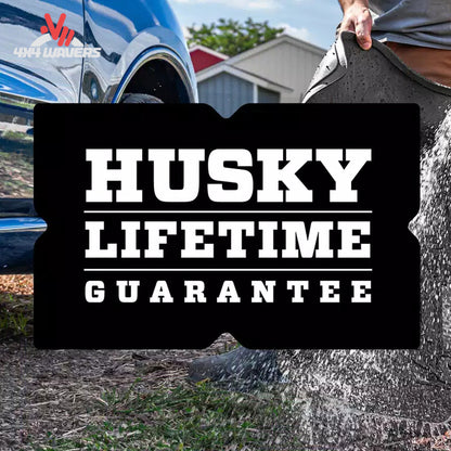 A black bumper sticker with bold white text reading 'HUSKY LIFETIME GUARANTEE' is shown in a lifestyle outdoor setting with a blue truck and a person splashing water.