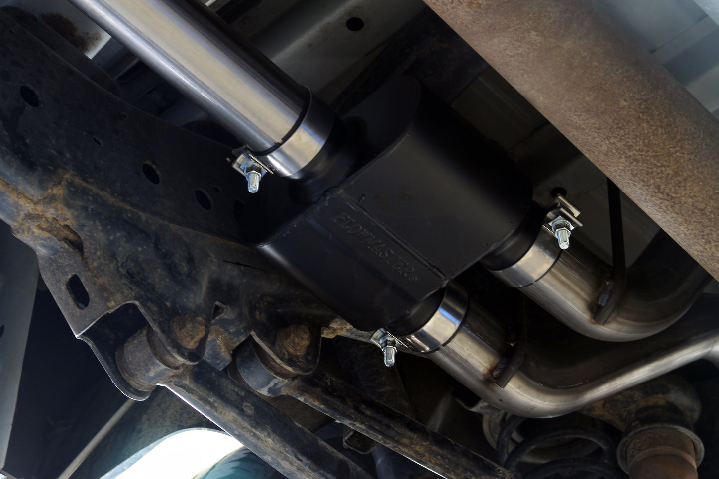 Flowmaster Outlaw Cat-back Exhaust System Kit installed on a vehicle, showcasing the stainless steel exhaust pipes and muffler.