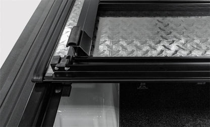 Open LOMAX hard folding tonneau cover on a 2020-2026 Jeep Gladiator with black finish and trail rail system, showing its low profile design.