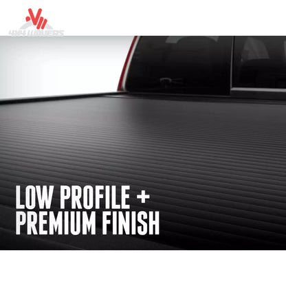 A close-up of a black textured truck bed cover with the text 'LOW PROFILE + PREMIUM FINISH' overlaid at the bottom left.